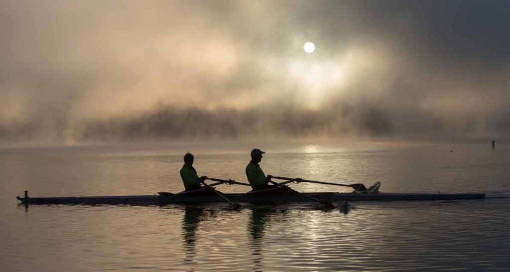 two people on a boat over calm water at daybreak