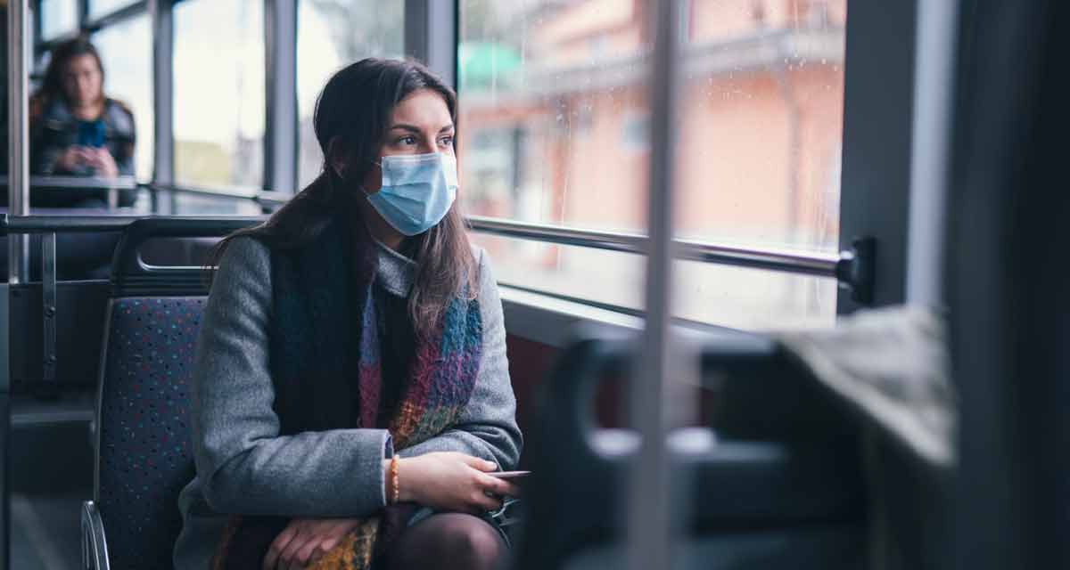 masked woman sitting on public transportation