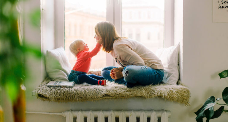 working mom sitting with toddler at home by window