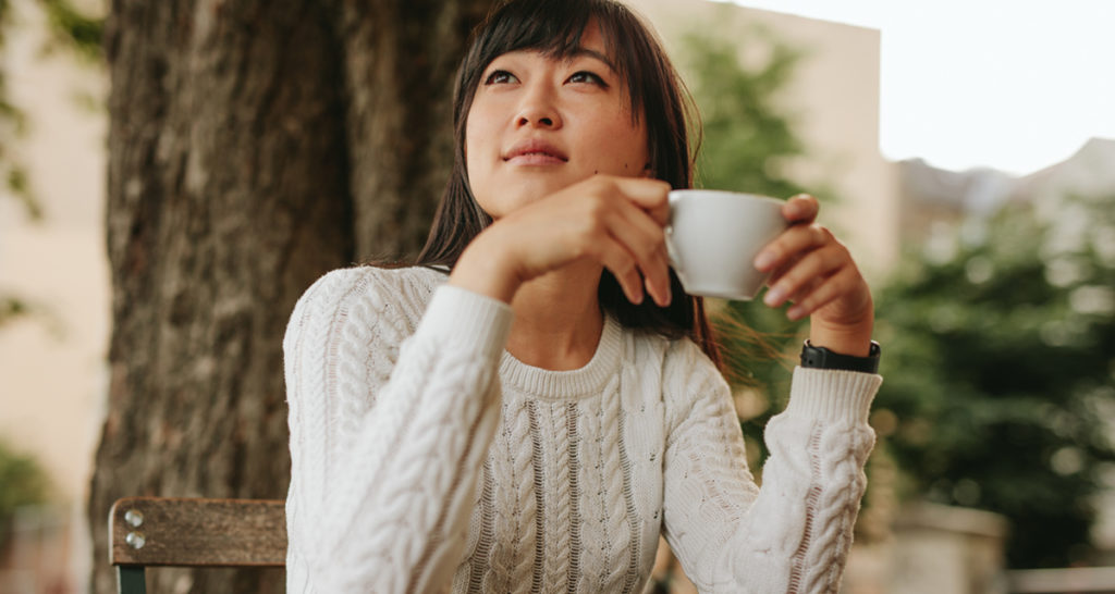 woman holding coffee cup looking reflective